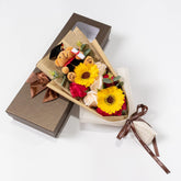 Ansuma front packaged bouquet in clear gift box showing red soap roses and plush bear, perfect ready-to-gift