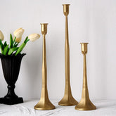 Denique front view of three gold taper candle holders showing coordinated heights and elegant silhouette