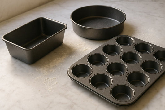 Loaf tin, round cake tin and muffin tray on a marble worktop with a light dusting of flour