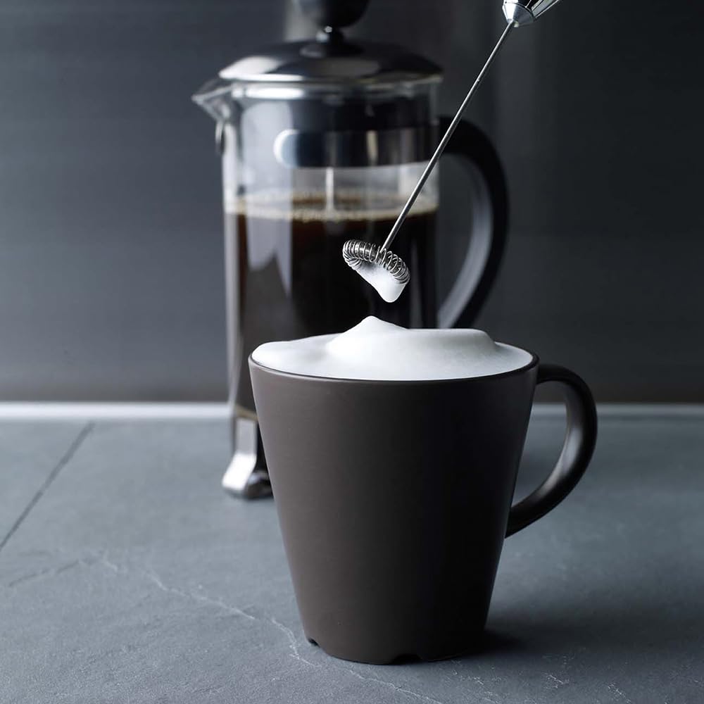 Aerolatte next to an espresso spoon for scale, highlighting compact convenience