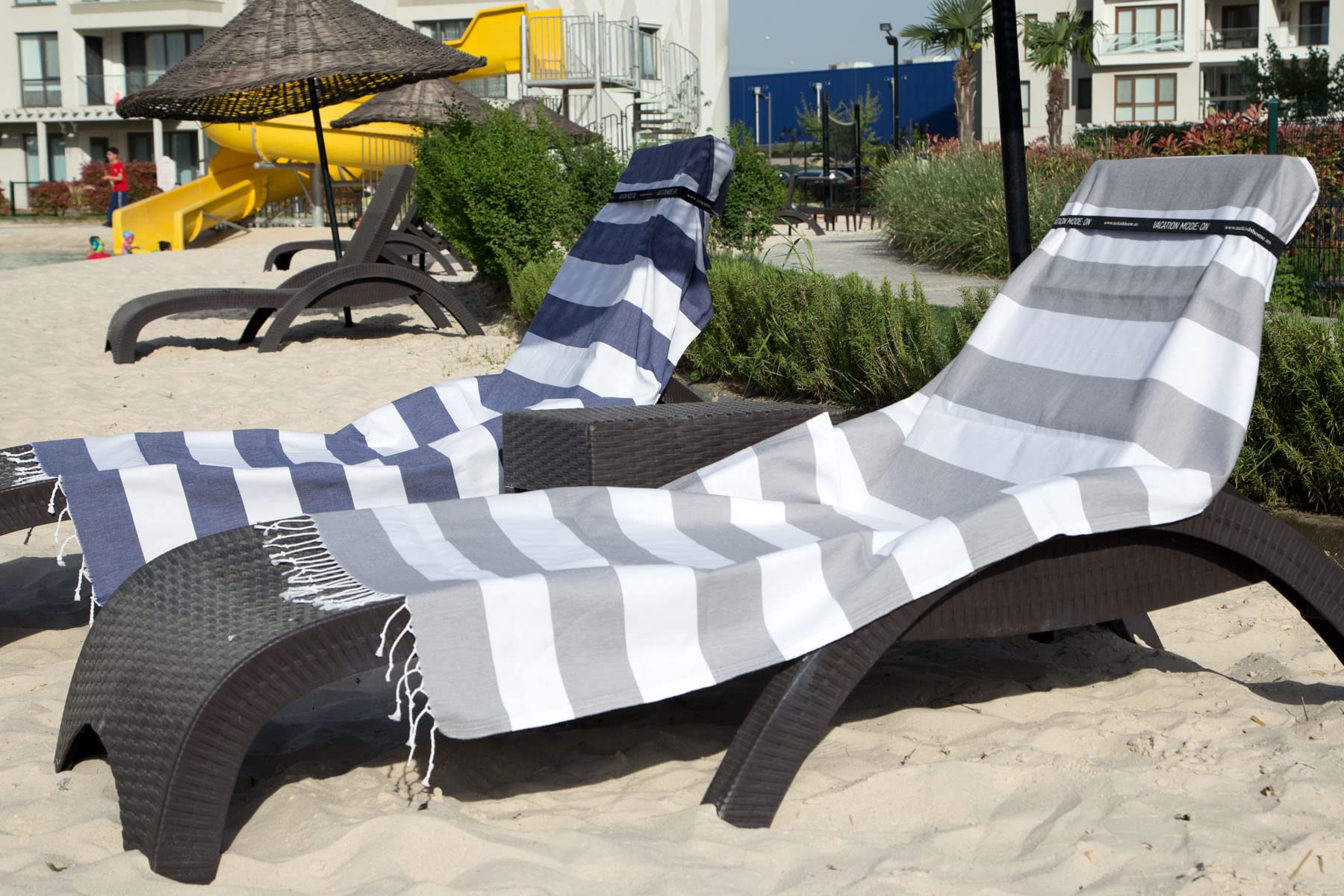 Clotho towel attached to a beach chair with band preventing wind slippage
