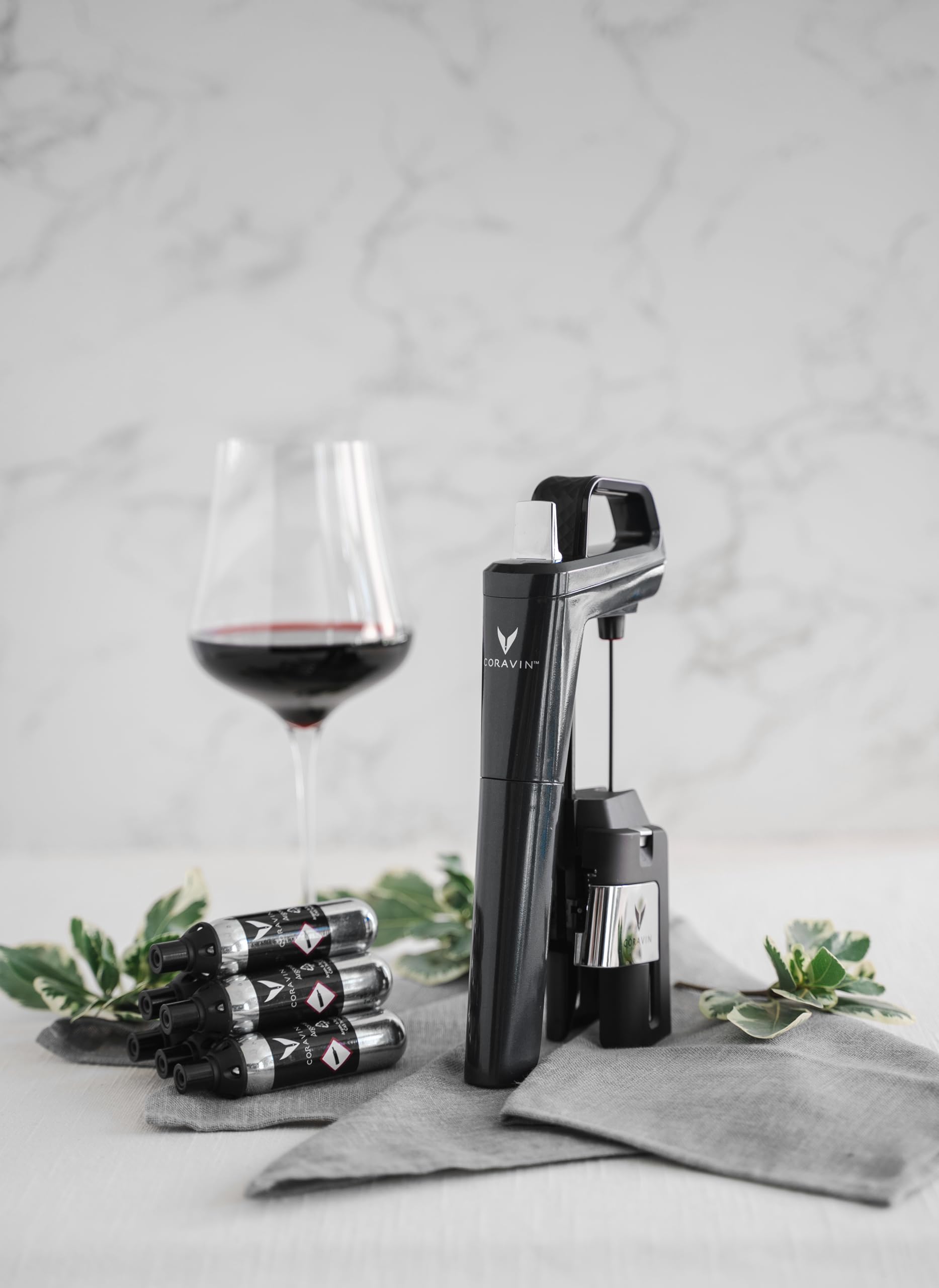 CORAVIN capsules on kitchen counter next to wine glass, preserving opened bottles at home