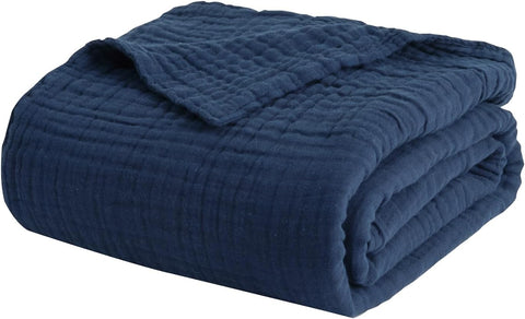 EMME folded blanket beside pillows showing bedroom styling and practical layering