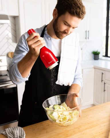 FinaMill being used at a stove with one hand, providing faster seasoning