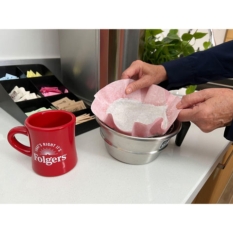 Folgers filter pack being placed in a commercial brewer for fast, consistent single-serve brews