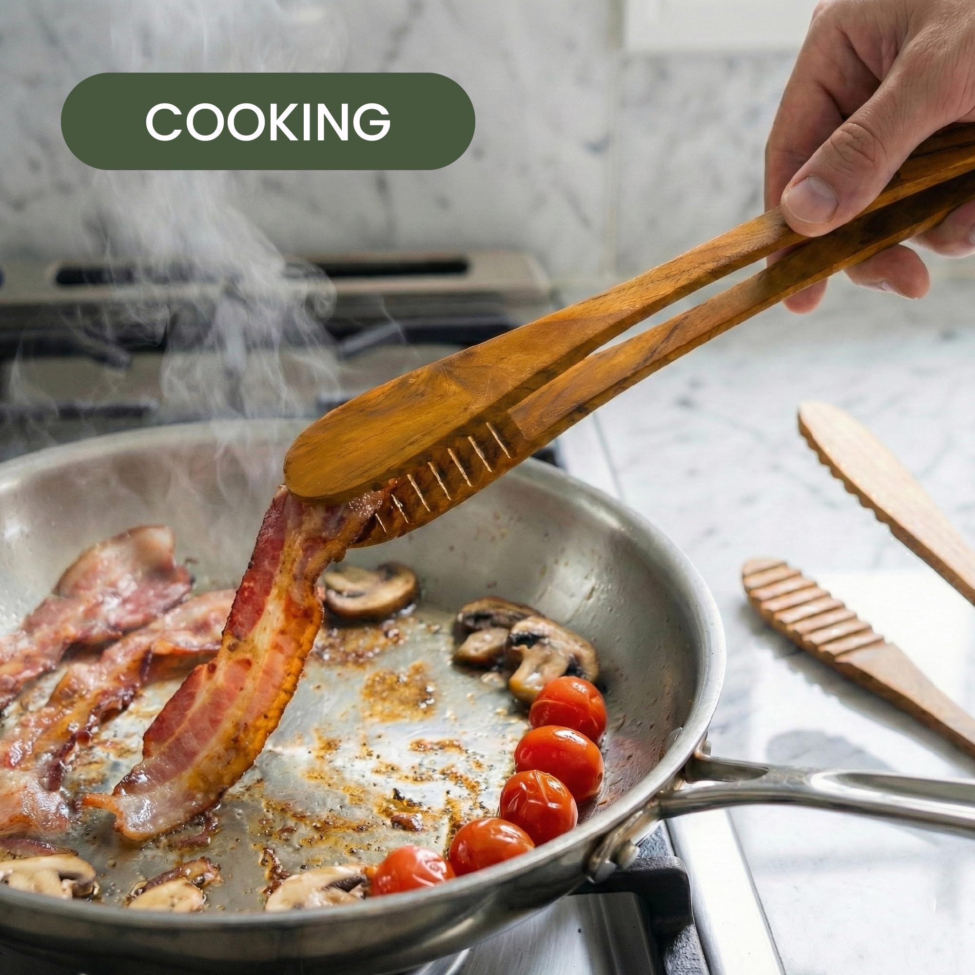 Graindi tongs flipping bacon in skillet protecting non-stick surface