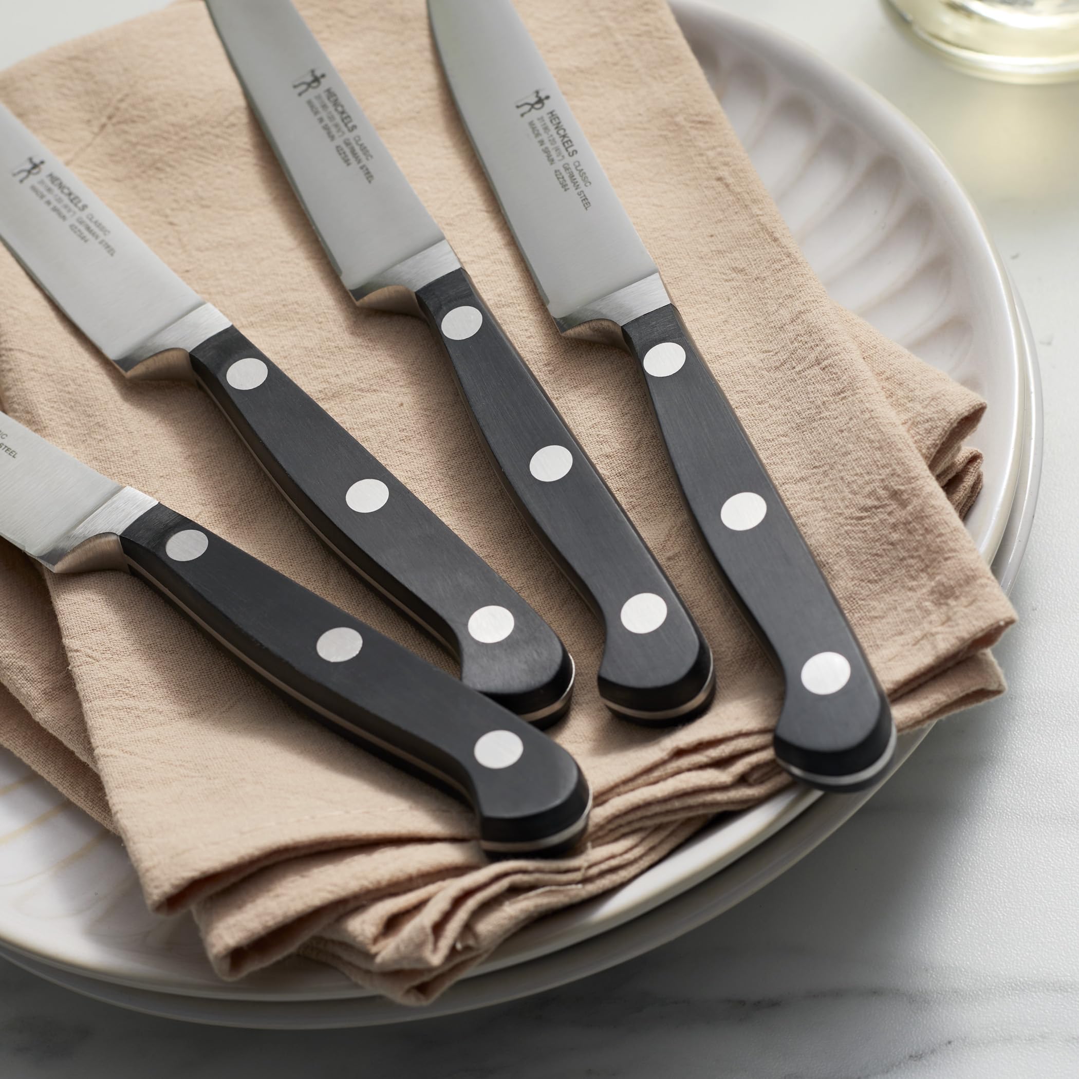 HENCKELS knives on a set table with steak showing stylish presentation and reliable performance