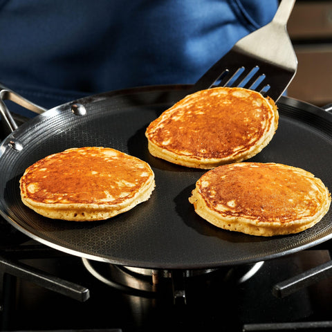 HexClad griddle being rinsed under water showing easy cleanup and dishwasher convenience
