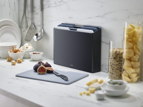 Joseph Joseph board beside a chef knife to show compact size and prep efficiency benefit