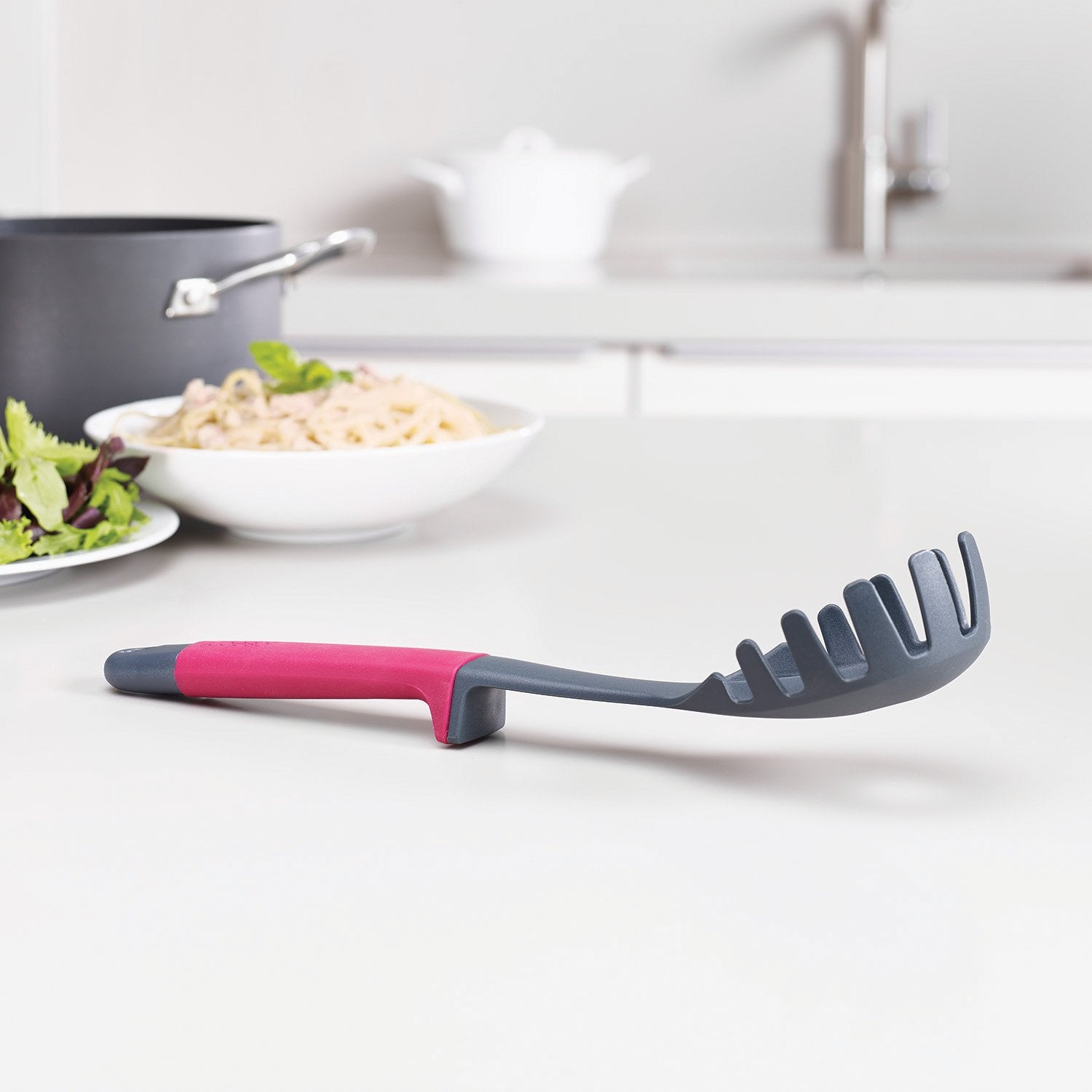 Joseph Joseph weighted handle resting on integrated rest keeping utensil heads off counters