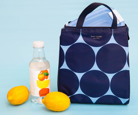 kate spade new york lunch bag in use on a commuter bench demonstrating portable convenience