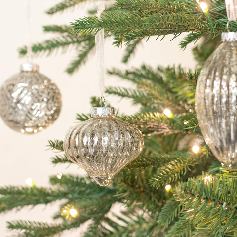 KI Store ball ornament hanging on tree branch adding vintage shimmer and depth