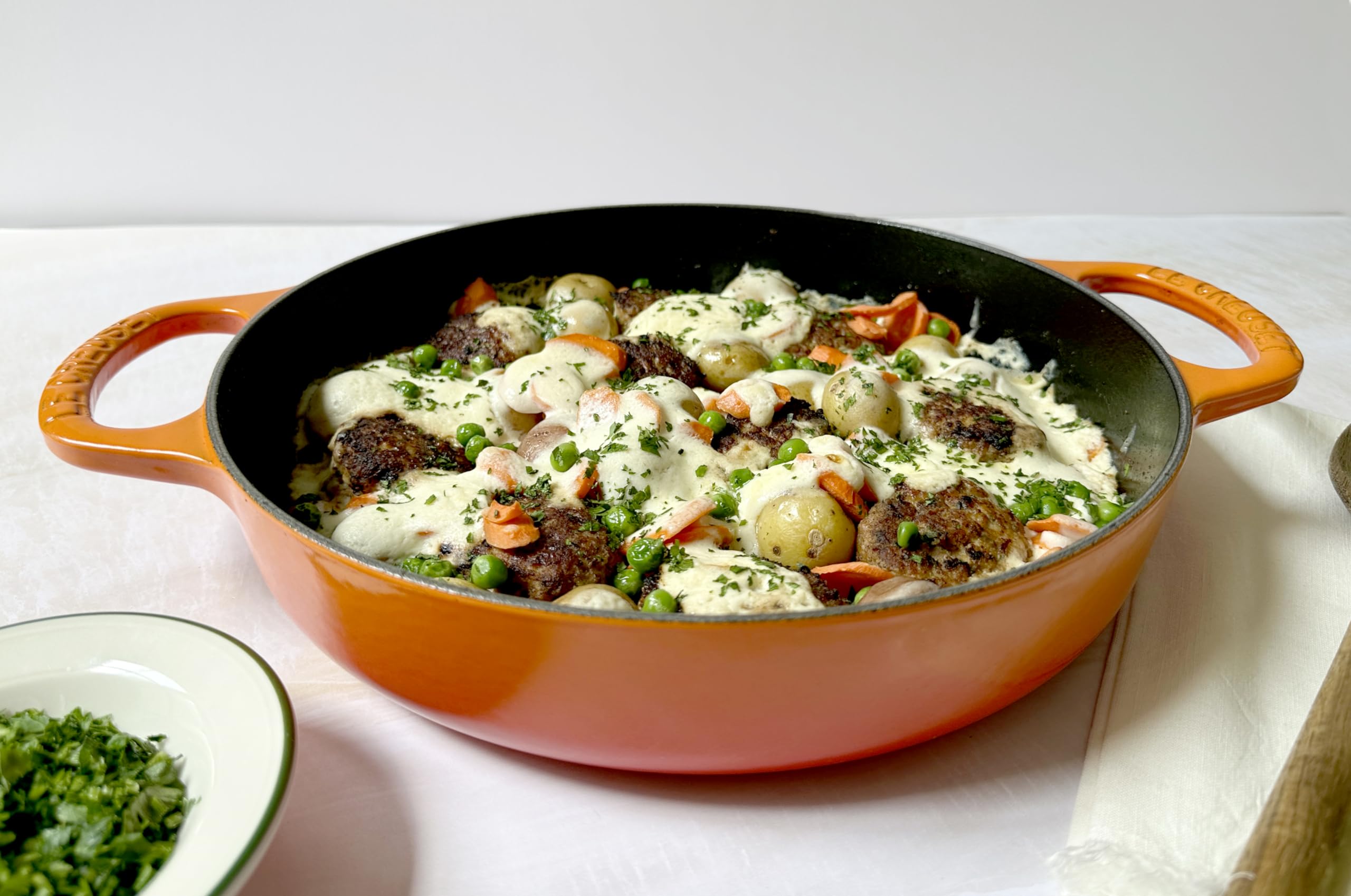 Le Creuset pan in an oven showing oven-safe capability and finishing convenience benefit
