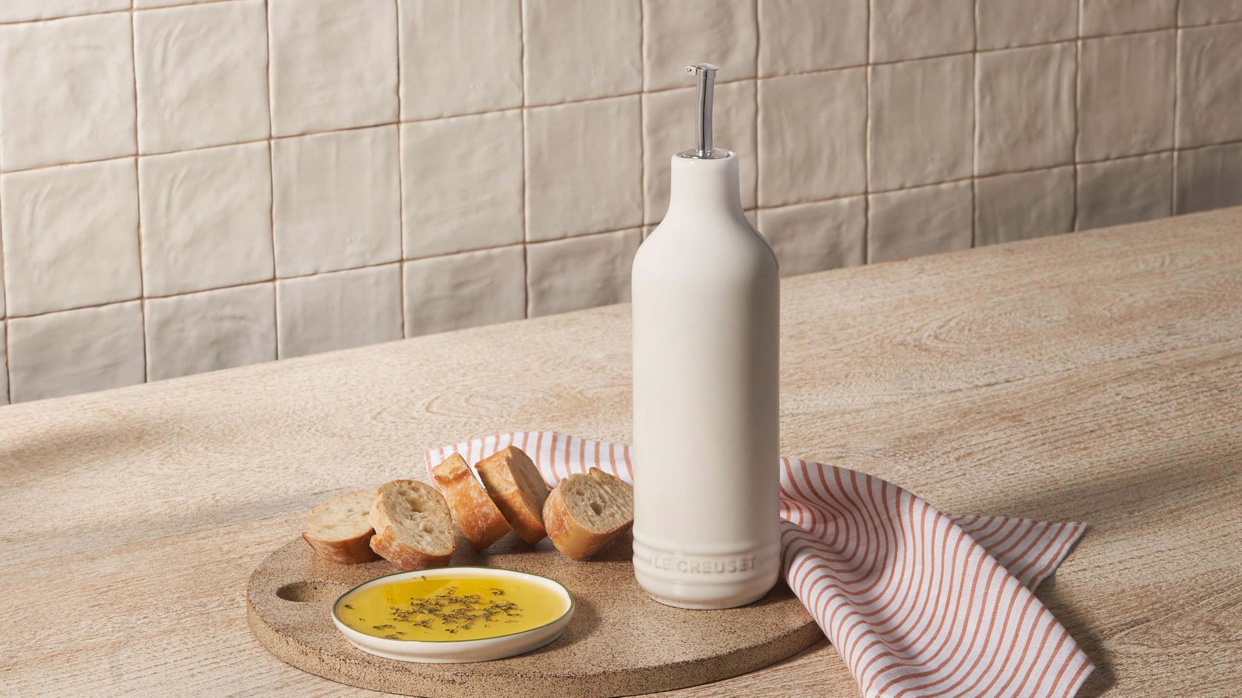 Le Creuset cruet next to standard oil bottle showing compact 20 oz capacity benefit