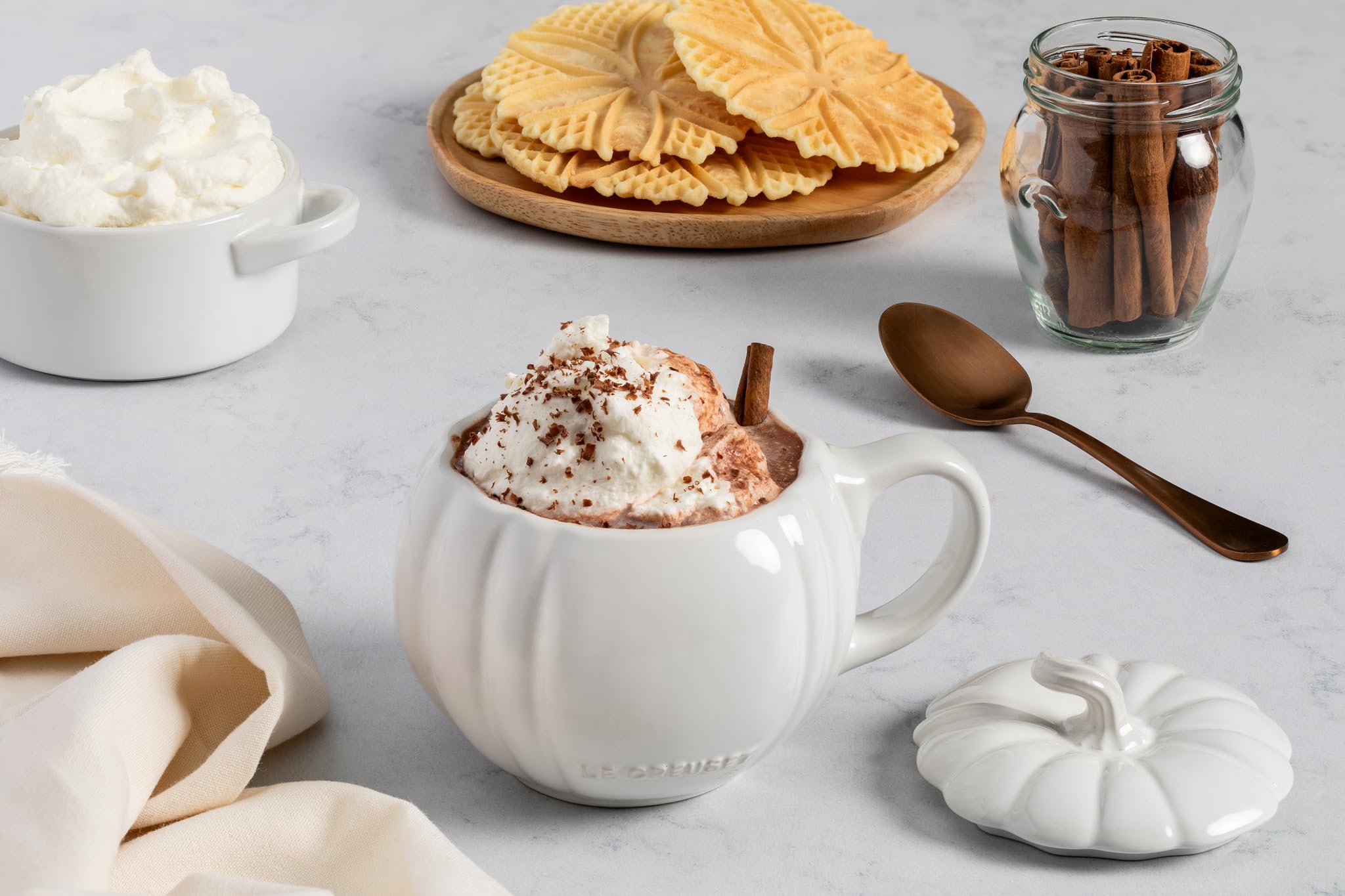 Le Creuset pumpkin mug next to a standard coffee cup for scale, clarifying 14 oz capacity