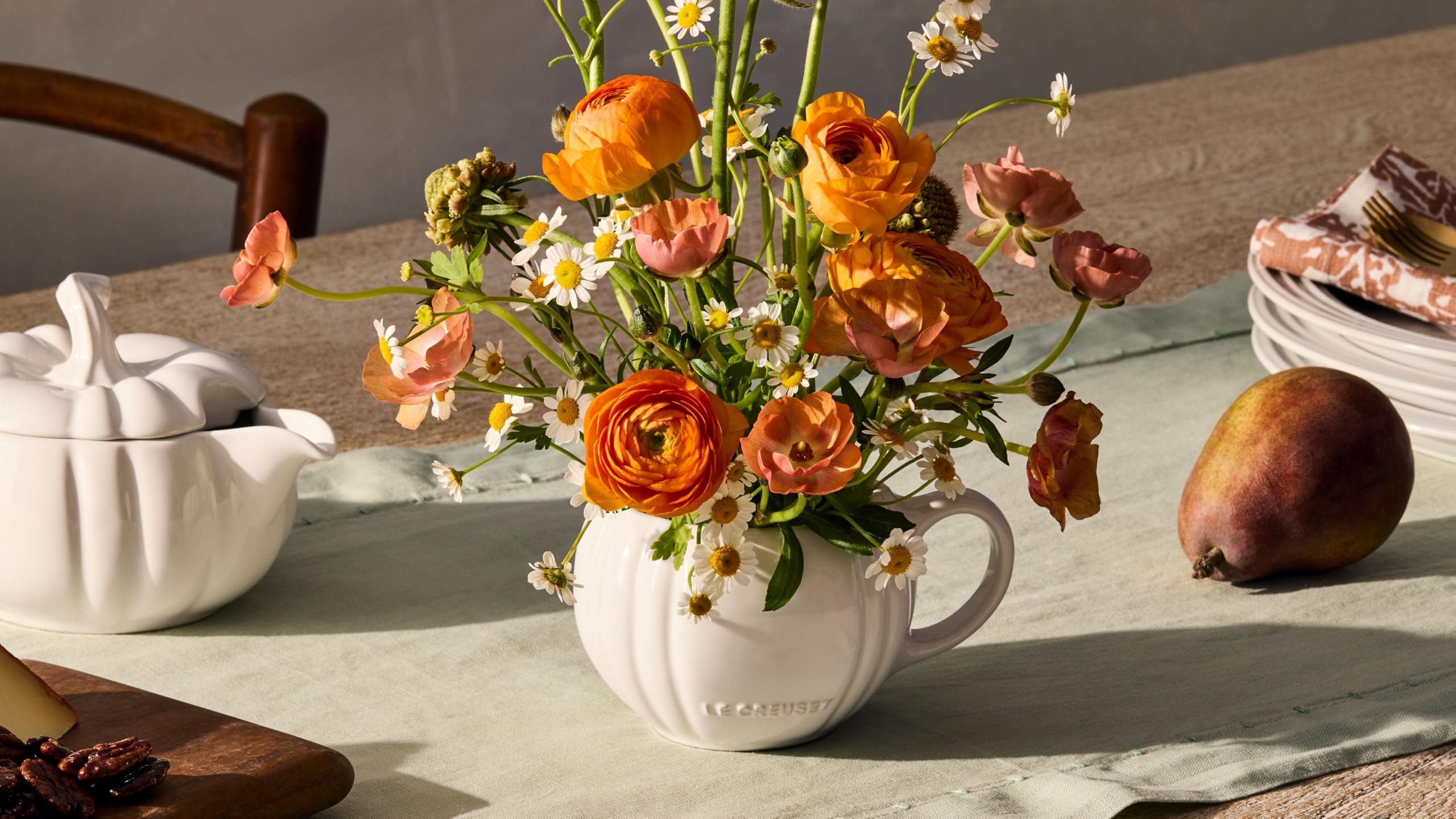 Le Creuset pumpkin mug styled on table with coordinating pieces, illustrating festive presentation