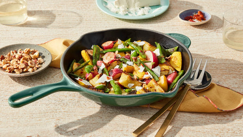 Le Creuset skillet on table with food illustrating attractive cerise finish benefit