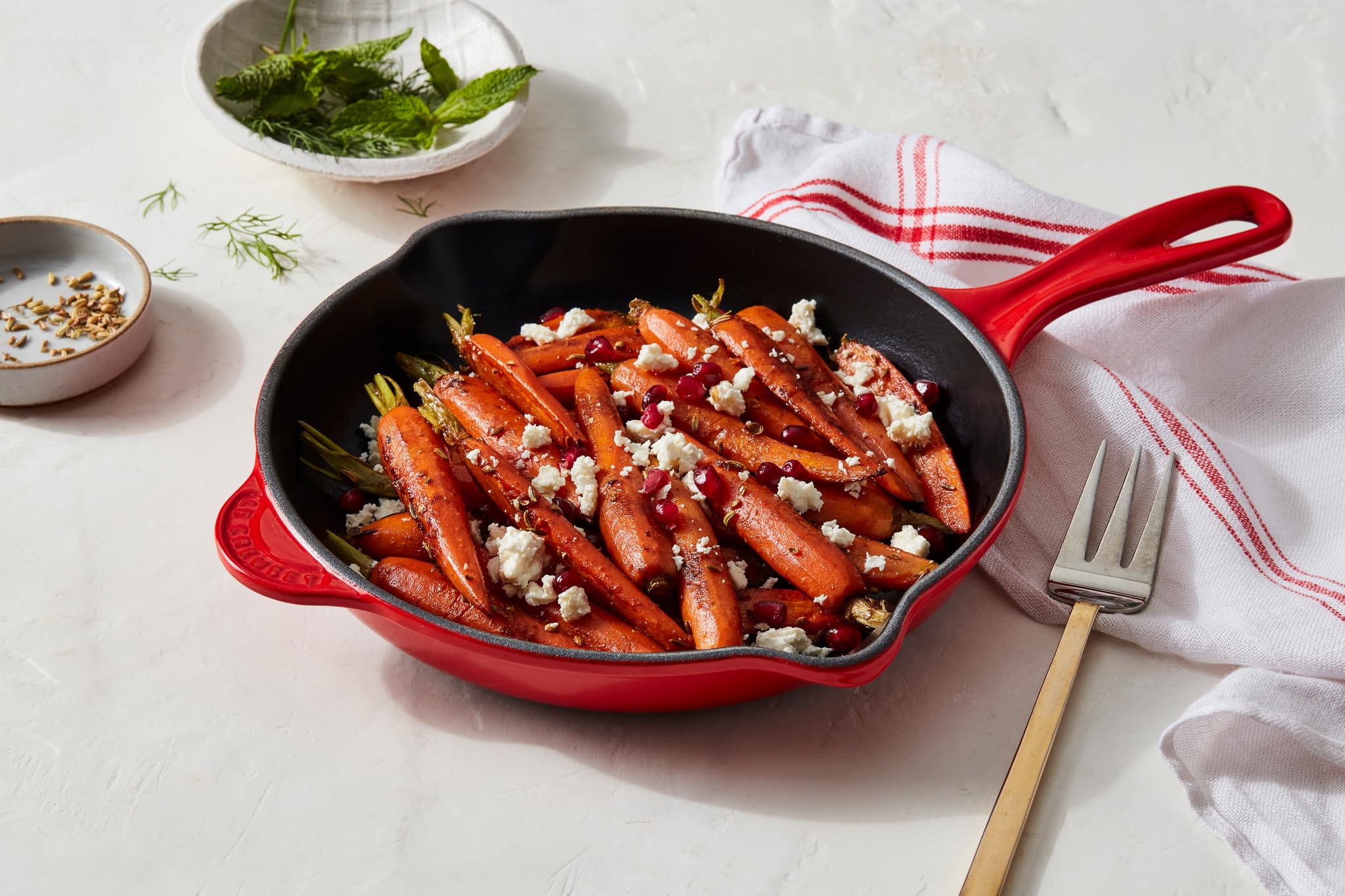 Le Creuset skillet beside measuring cup to show 9-inch size and portability benefit