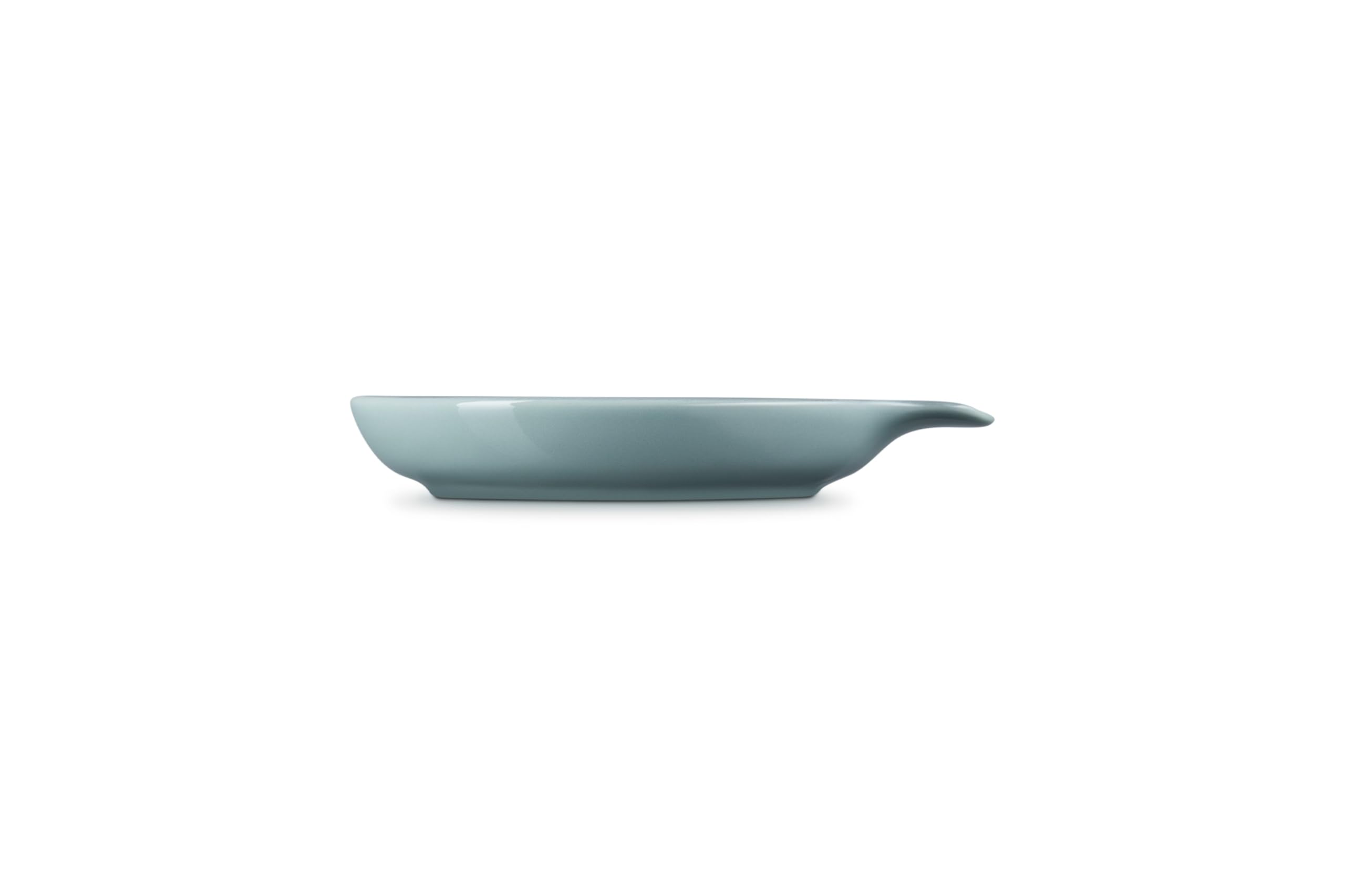 Le Creuset spoon rest holding a wooden spoon on stovetop to protect counters