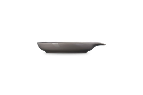 Le Creuset spoon rest holding a wooden spoon beside a pot showing spill protection benefit