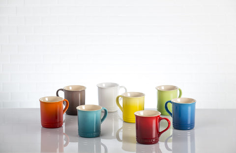 Le Creuset Vancouver Mug Peche next to a hand for size comparison and practical scale