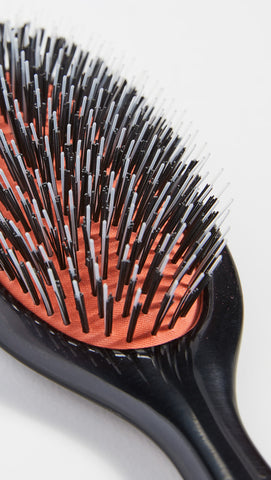 Hand holding Mason Pearson handy brush to show size and ergonomic grip for comfortable styling