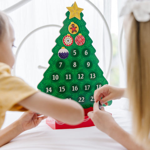 Melissa & Doug child placing an ornament on the tree demonstrating hands-on play and fine-motor practice benefit
