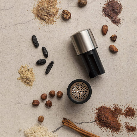 Microplane mill with nutmeg and cinnamon nearby showing versatile spice use