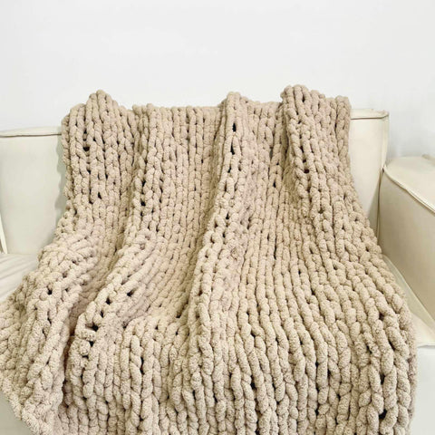 MocaDng blanket next to an armchair for size comparison showing generous 100 x 100 inch coverage