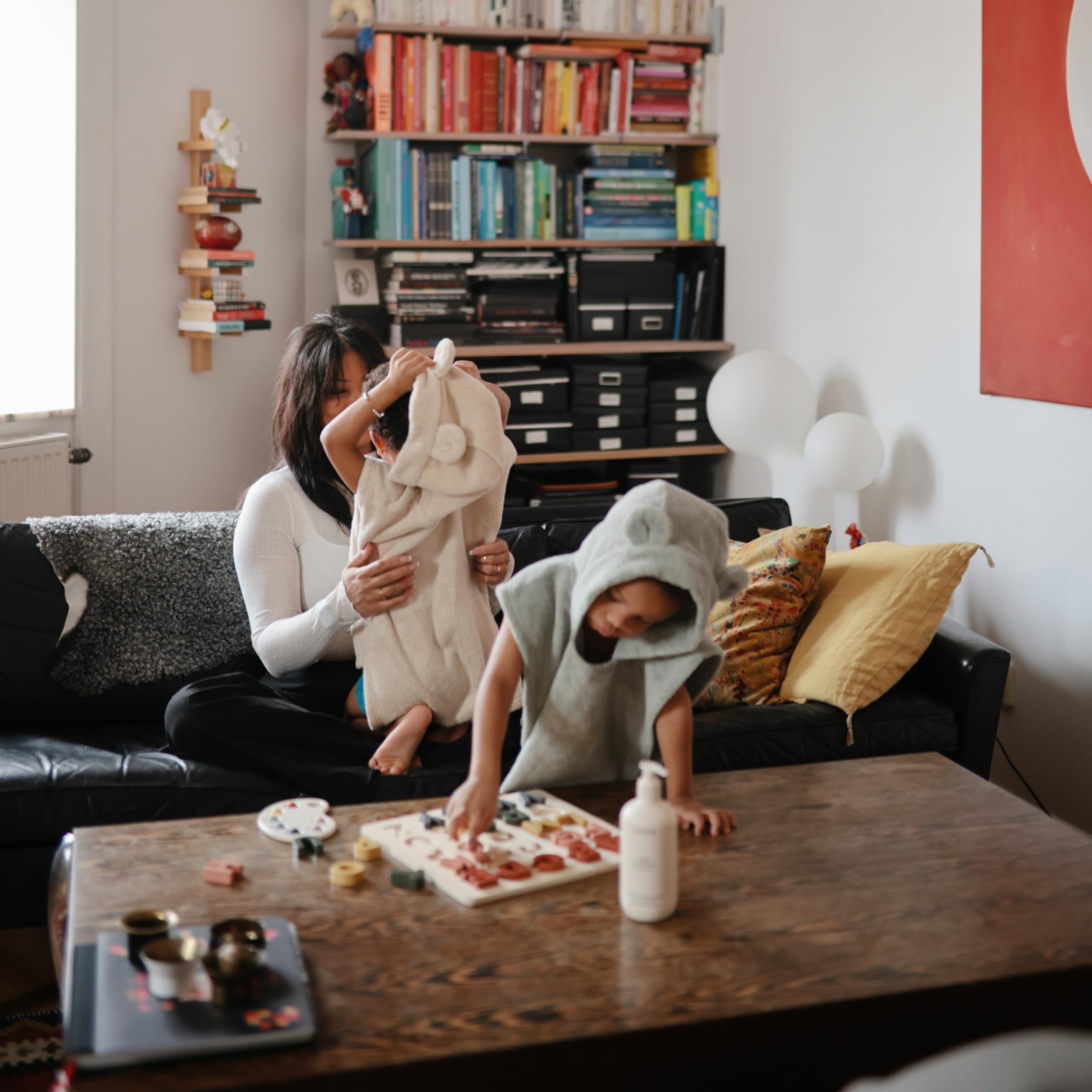 mushie poncho next to small toy showing size and scale for toddlers