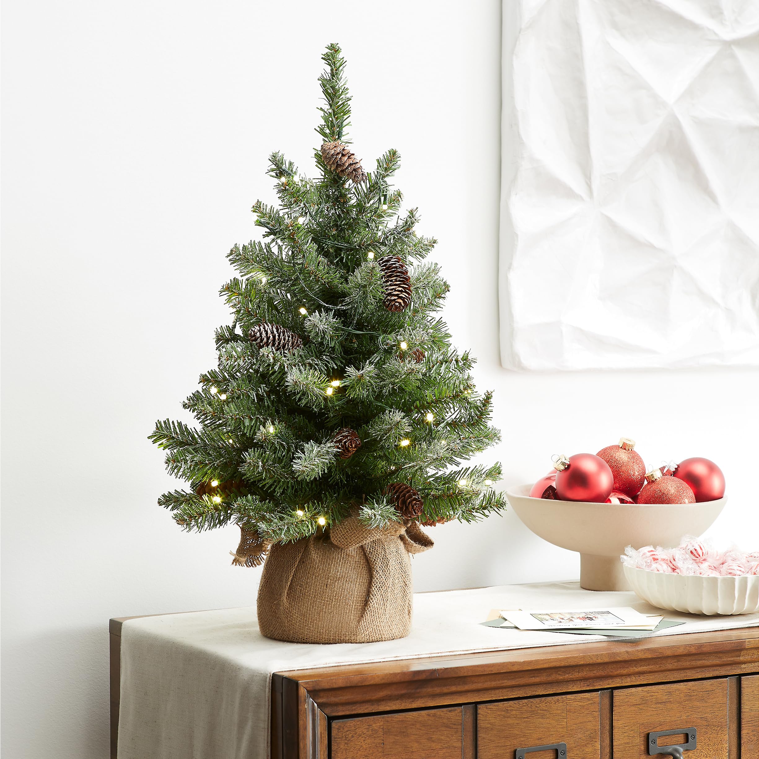 National Tree Company burlap bag base with tree next to coffee mug for scale, compact size advantage