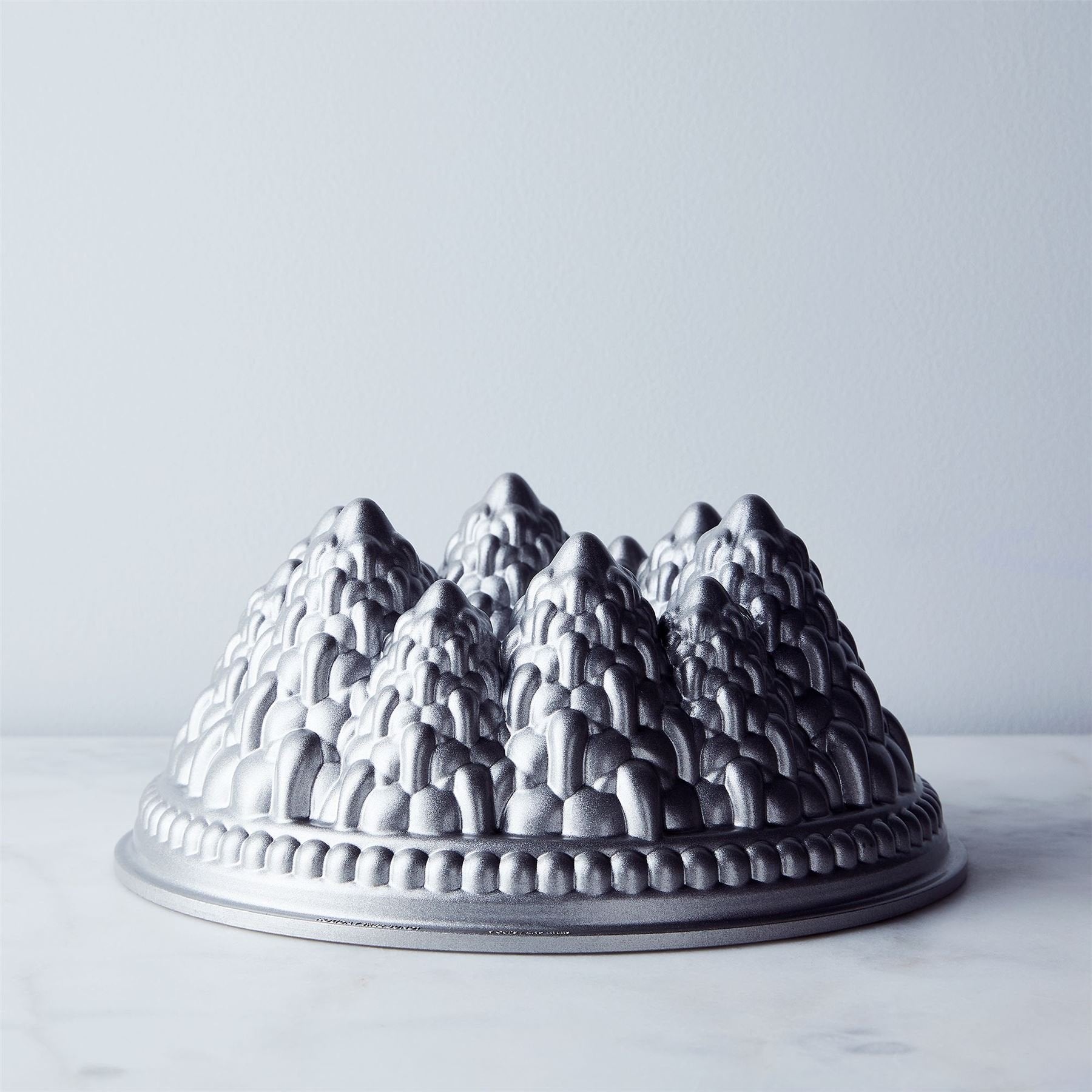Nordic Ware Pine Forest Bundt cake on rustic table, showing plated presentation for gatherings