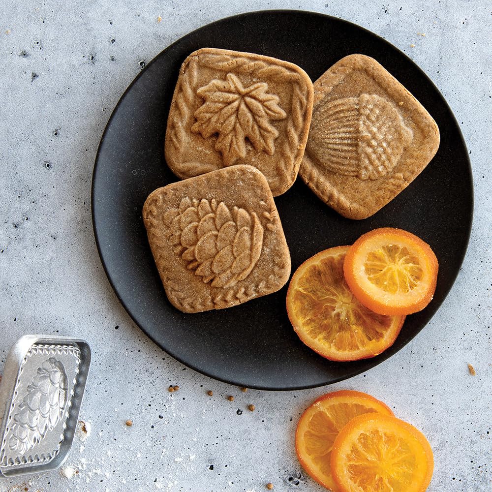 Nordic Ware cookie stamp pressing into chilled dough, produces clear embossed cookie patterns