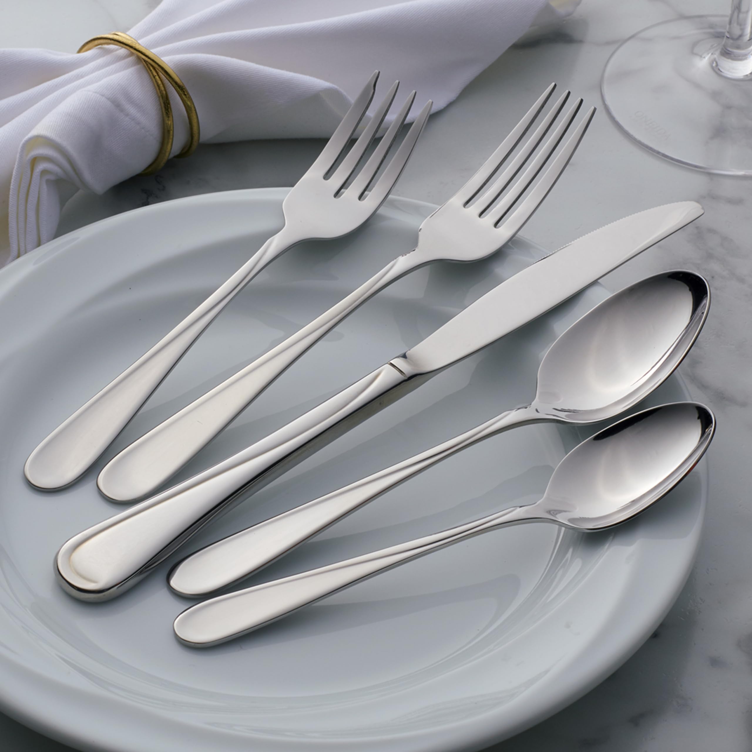 Lifestyle dining scene with Oneida Flight flatware on a wooden table conveying everyday elegance