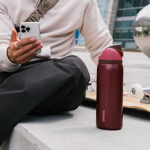 Owala bottle beside backpack outdoors showing portability and active lifestyle use