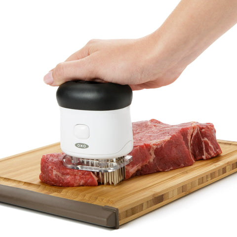 OXO tenderizer in use on steak illustrating quicker flavor absorption benefit