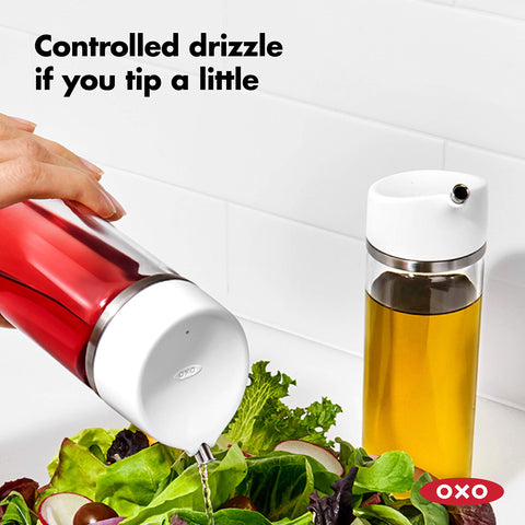 OXO dispenser tipped slightly for a light drizzle finishing a salad with precision