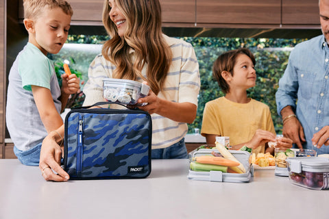PackIt Sporty Camo Navy buckle handle clipped to a backpack for easy transport