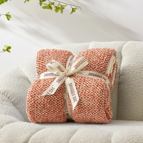 Snuggle Sac folded next to a book showing 50 x 60 inch scale and portability