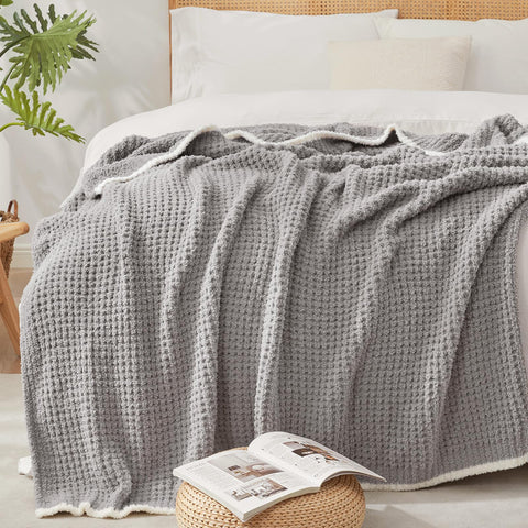 Snuggle Sac beside a book for scale showing 50x60-inch travel-friendly size
