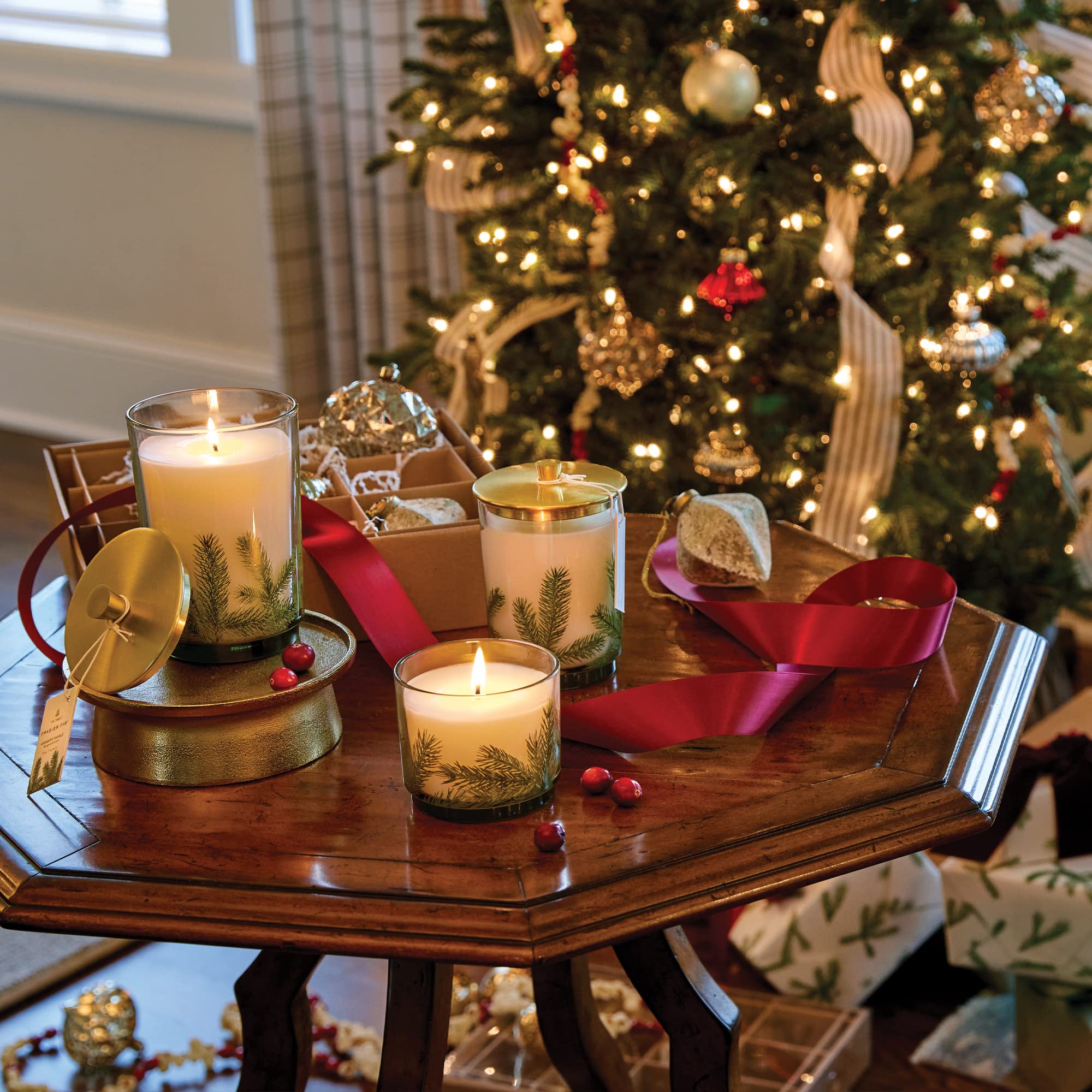 Thymes Frasier Fir candle beside holiday decor showing size and styling benefit
