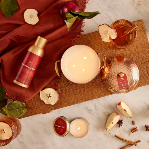 Thymes candle next to hand for scale conveying size and decorative versatility