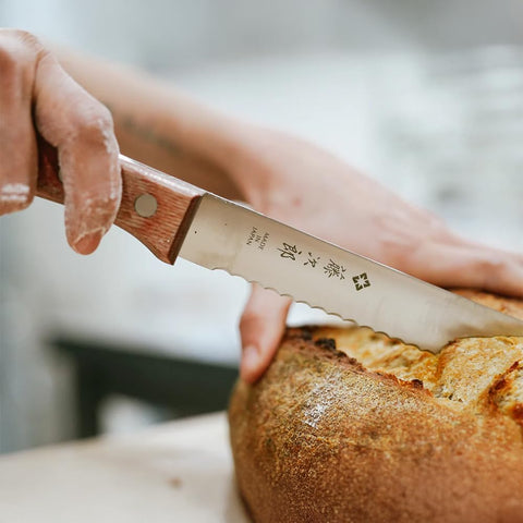 Tojiro knife slicing artisan loaf, demonstrating clean even cuts without crushing