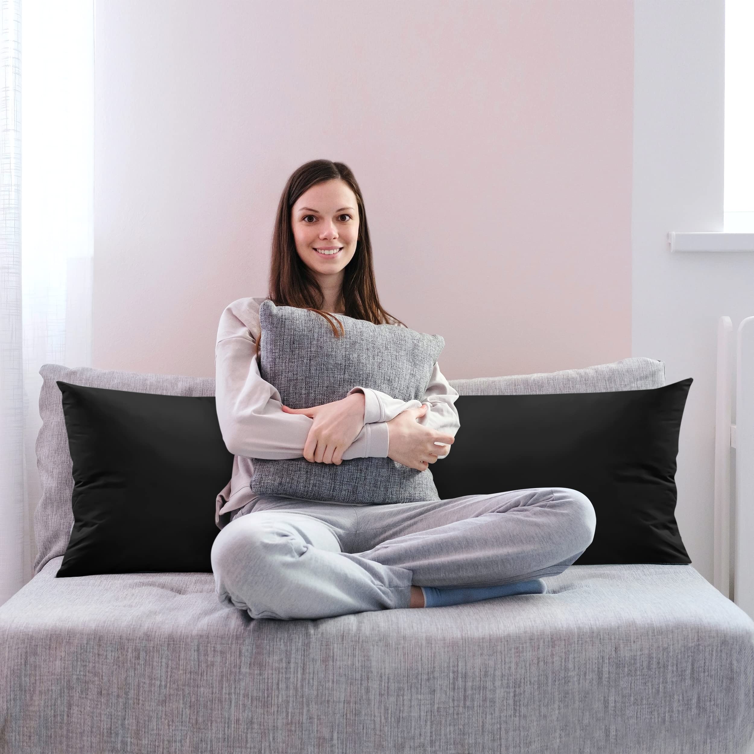 Utopia Bedding body pillow next to a person to show 20 x 54 inch scale