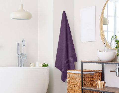 Utopia Towels plum beside person showing 35x70 inch size and scale