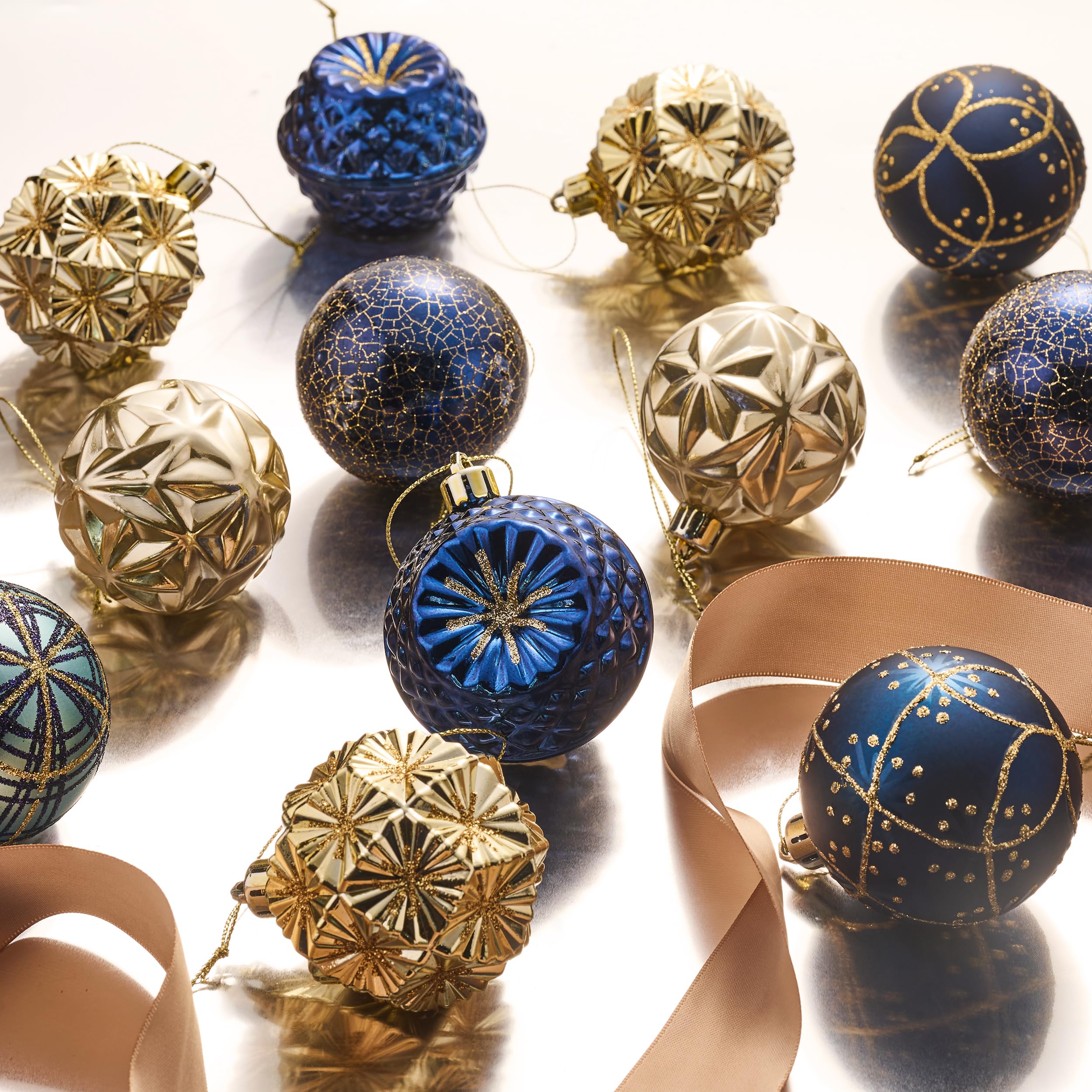 Valery Madelyn ornaments hanging on a lit tree adding cohesive blue and gold sparkle