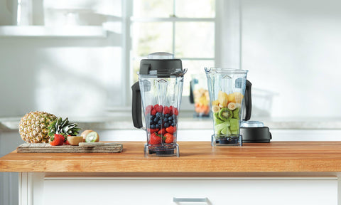 Vitamix 64 oz container next to a coffee mug to show capacity and household scale benefits
