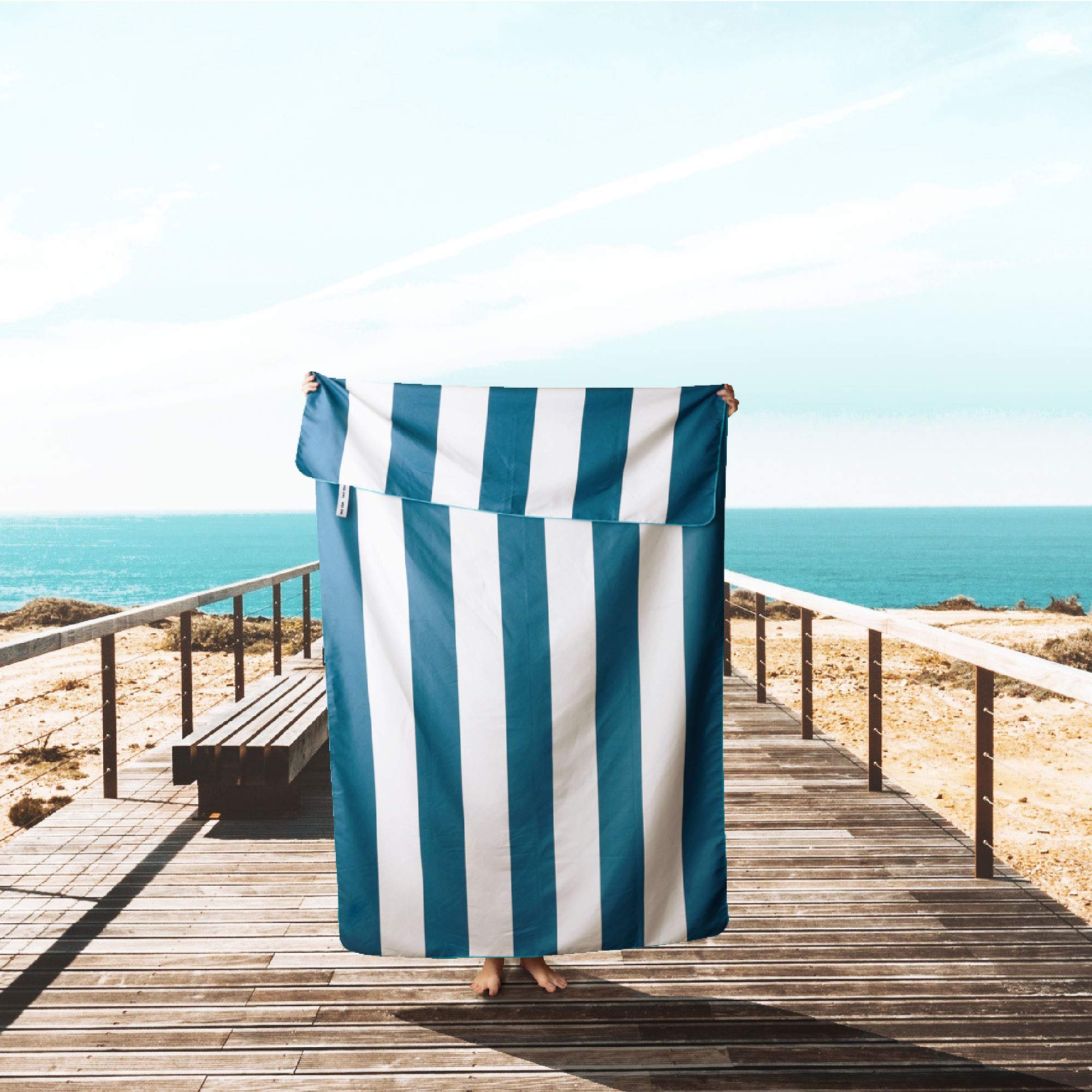 Wise Owl Outfitters towel being shaken to remove sand, keeping it clean and light