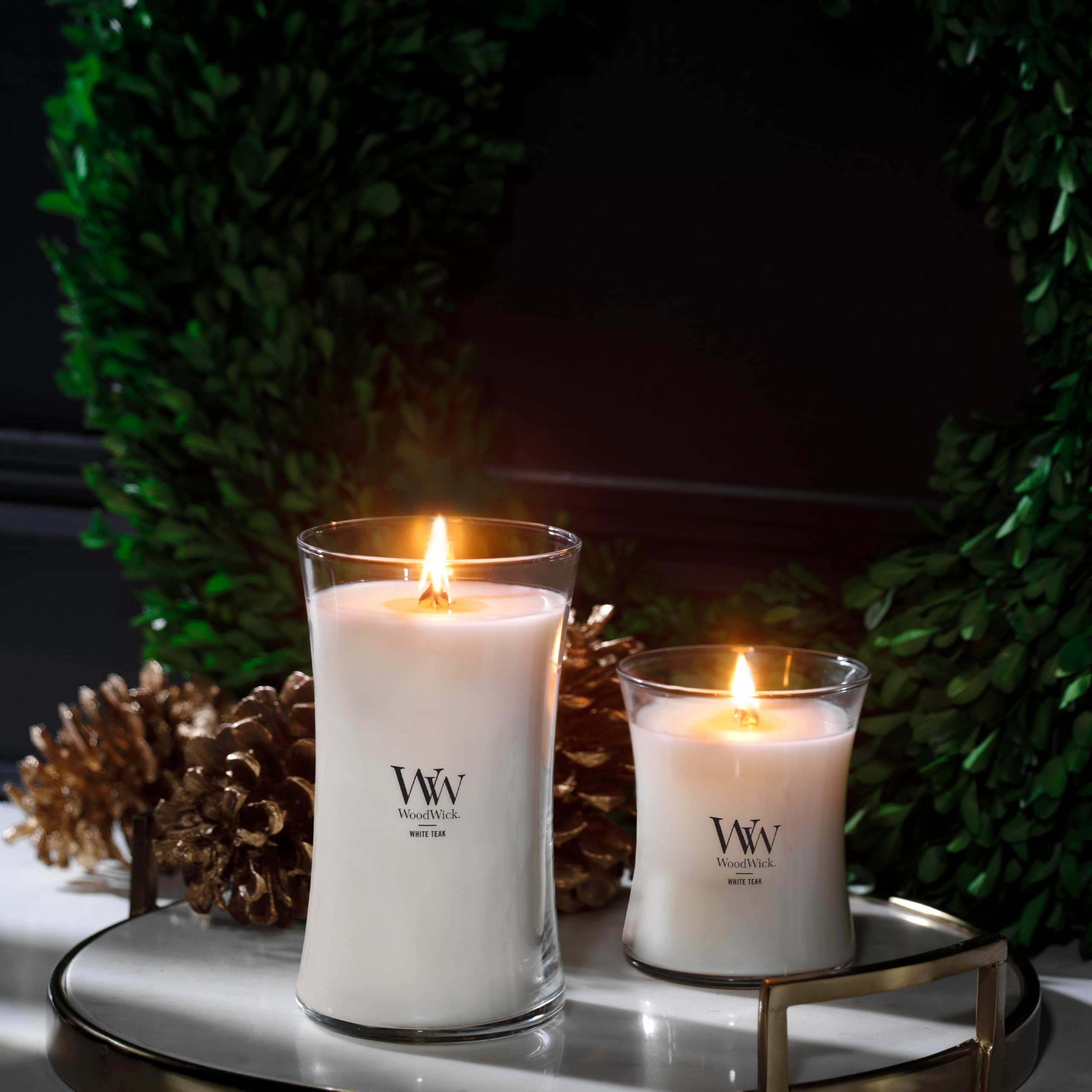 WoodWick hourglass candle beside a book for scale showing size and long-lasting burn benefit
