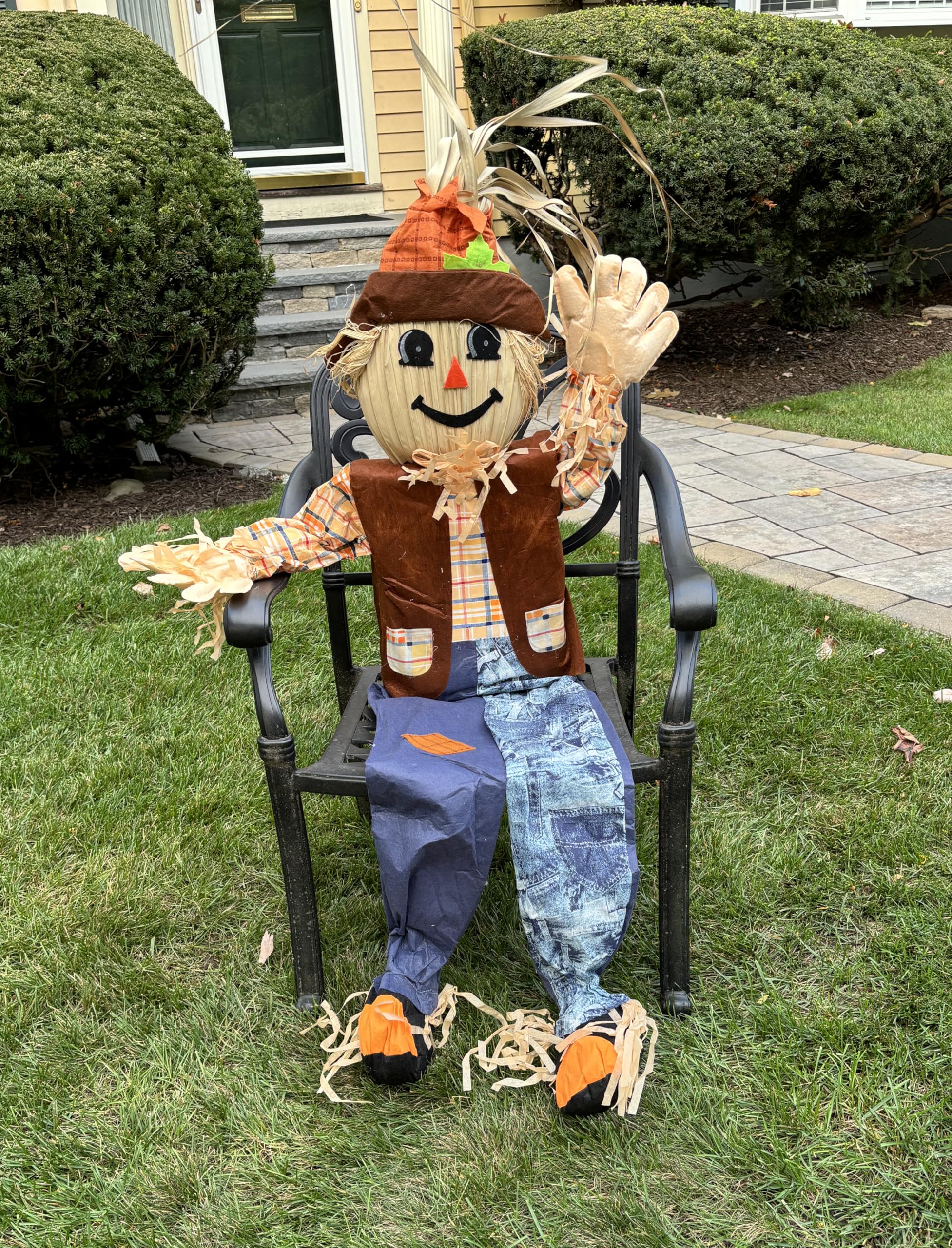 Worth Imports scarecrow seated on a porch styled with pumpkins for welcoming, low-effort fall decor